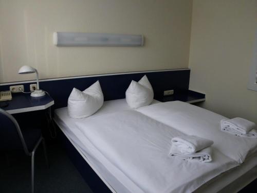 a bedroom with a white bed with towels on it at Central-Hotel Eberswalde in Eberswalde-Finow