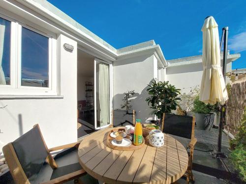 - une table en bois avec des chaises et un parasol sur la terrasse dans l'établissement Nestor&Jeeves - TERRASSE DU SUD - Central - Terrace, à Nice