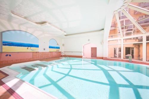 a swimming pool in a building with a large window at Strandhotel Luise von Preussen in Zinnowitz