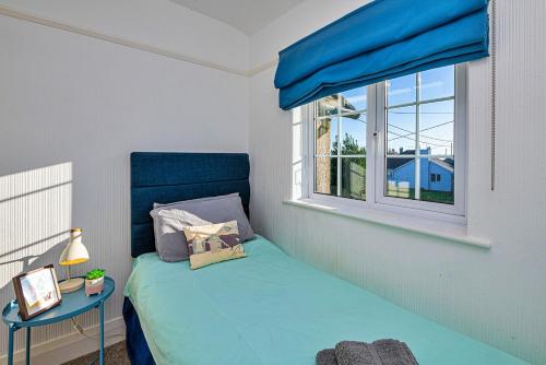 a small bedroom with a blue bed and a window at Finest Retreats - Hillcroft in Abersoch