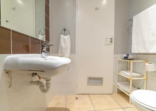 a white bathroom with a sink and a toilet at Peninsula All Suite Hotel by Dream Resorts in Cape Town