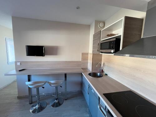 a kitchen with a counter and two stools in it at Logis Les Forges in Arvillard