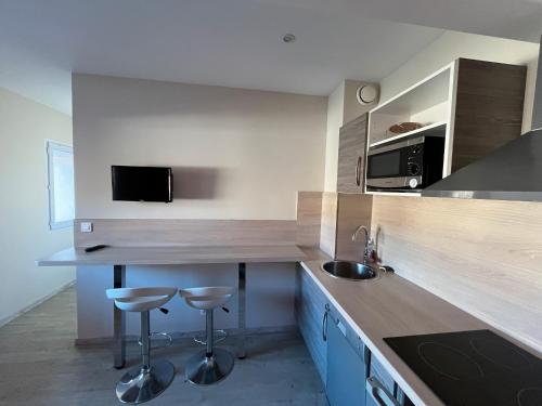 a kitchen with a counter and two stools in it at Logis Les Forges in Arvillard