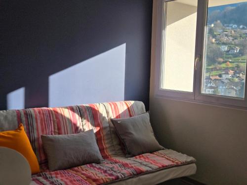 a couch with pillows in a room with a window at Logis Les Forges in Arvillard