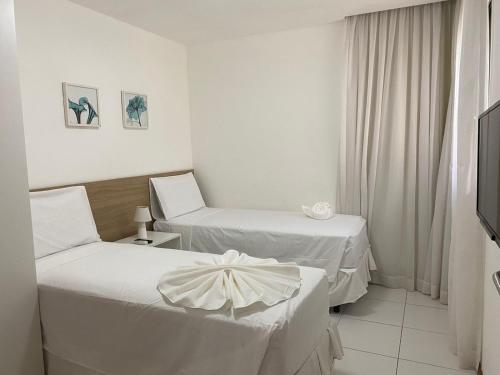 a hotel room with two beds and a television at ILOA 02 quartos térreo 03J in Barra de São Miguel