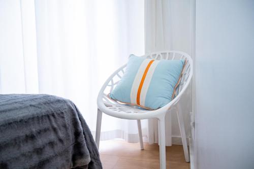 a white chair with a pillow on it next to a window at By the Sea - Nazaré in Nazaré