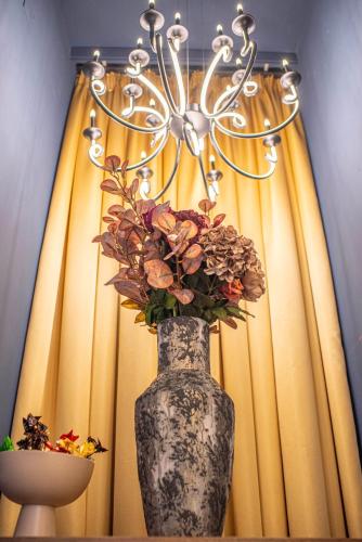 a vase with flowers in front of a window at Paj Hotelul Retreat & Spa in Sinaia