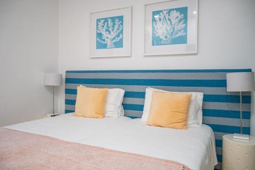 a bedroom with a blue and white bed with orange pillows at By the Sea - Nazaré in Nazaré