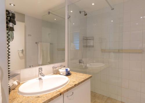 a white bathroom with a sink and a shower at Peninsula All Suite Hotel by Dream Resorts in Cape Town