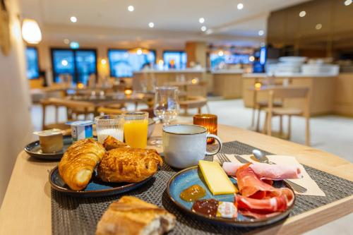 a table with plates of breakfast food on it at Hotel Bhoma Troyes in Troyes