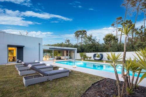 a swimming pool with chaise lounges next to a house at Portugal Active Hábito's Lodge in Viana do Castelo