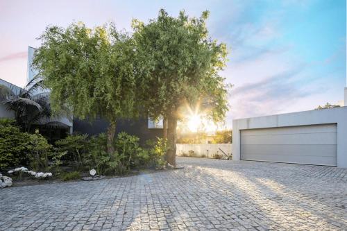 a tree in front of a house with a garage at Portugal Active Hábito's Lodge in Viana do Castelo