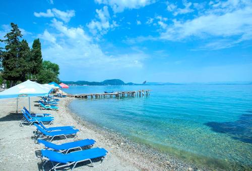 a beach with lounge chairs and a dock in the water at Valtes Blue by Vintage Travel in Corfu