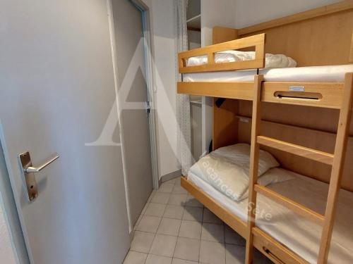 Cette petite chambre comprend des lits superposés et une porte. dans l'établissement A 2 pas des plages pour 4 personnes, à Sète