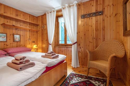 two beds in a room with wooden walls and a chair at Apartment Corti Garden in Campodolcino