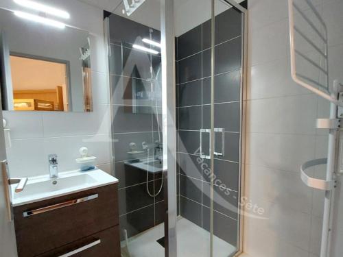 une salle de bain avec une douche en verre et un lavabo dans l'établissement A 2 pas des plages pour 4 personnes, à Sète