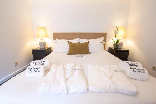 a bedroom with a white bed with towels on it at PortugalActive Beach Flat in Viana do Castelo