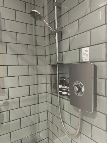 a shower with a shower head in a bathroom at Hampton Court Snug Walk to train & palace in East Molesey