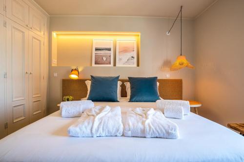 a bedroom with a large white bed with blue pillows at BlueGreen Beach Apartment in Viana do Castelo