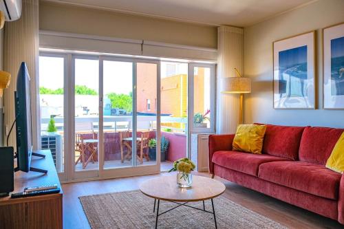 a living room with a red couch and a table at BlueGreen Beach Apartment in Viana do Castelo
