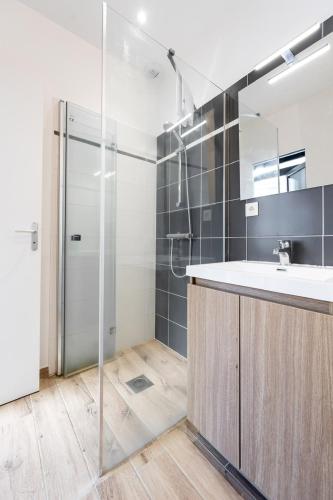 a bathroom with a shower and a sink and a mirror at Koaloft in Lorient