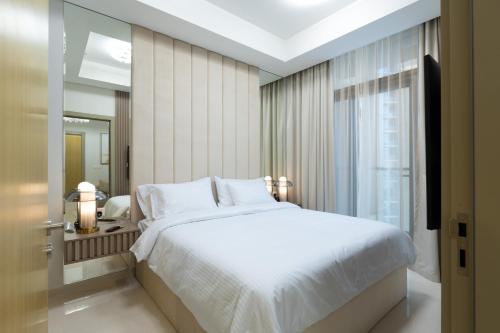 a bedroom with a large white bed and a window at Keyrock Aykon Tower, Business Bay - Pool & Gym in Dubai