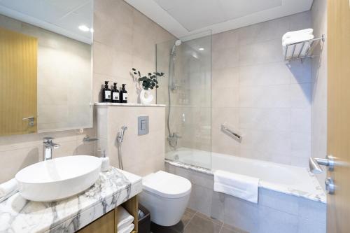 a bathroom with a sink and a toilet and a tub at Keyrock Aykon Tower, Business Bay - Pool & Gym in Dubai