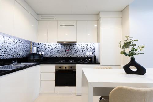 a kitchen with white cabinets and a table with a plant at Keyrock Aykon Tower, Business Bay - Pool & Gym in Dubai