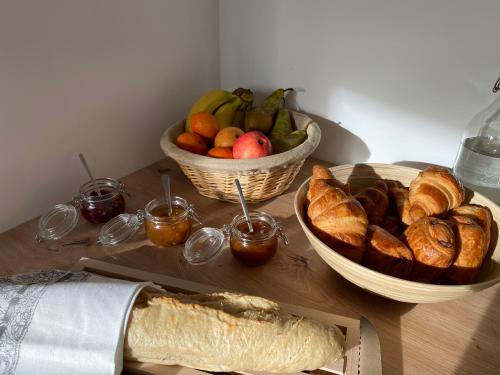a table with two baskets of bread and a bowl of fruit at La Tour en Seine in Les Authieux-sur-le-Port-Saint-Ouen