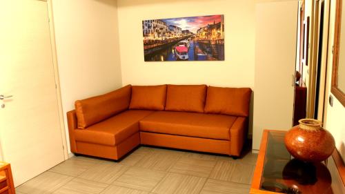an orange couch in a living room with a painting at Oasi Brembate Bed and Breakfast in Brembate