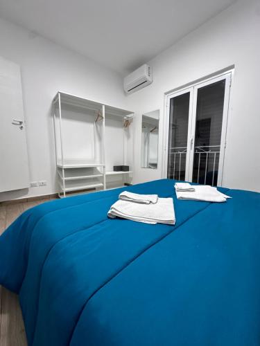 een blauw bed in een witte kamer met handdoeken erop bij abela 9 in Palermo