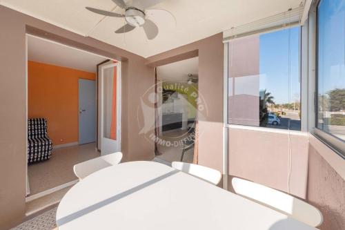 une table et des chaises dans une pièce avec une fenêtre dans l'établissement AS21116 - P2 centre ville dans une résidence à 200m de la plage, au Grau-du-Roi