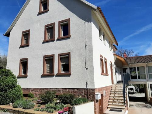 Casa blanca con ventanas marrones y escaleras en Fiore Gästezimmer, en Michelrieth