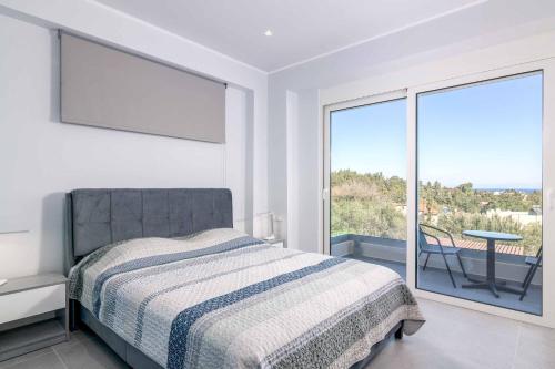 a white bedroom with a bed and a large window at Villa Anastazia in Koskinou