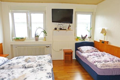 a bedroom with two beds and a tv on the wall at Messe-Zimmer TuS-Treff in Düsseldorf