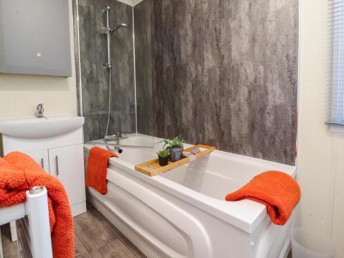 a bathroom with a bath tub with orange towels at 17 Birchwood Close in Brown Moss Side