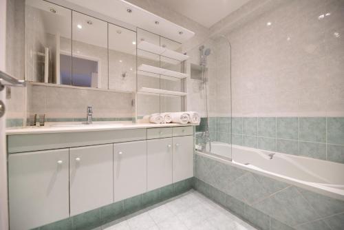une salle de bain avec une baignoire et un lavabo et une baignoire tubermottermott dans l'établissement CIA - Pereire, Spacious Flat with Balcony, à Paris