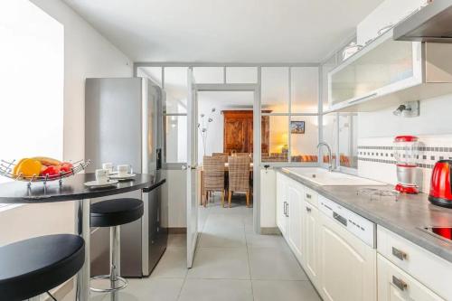 une cuisine avec des armoires blanches et un comptoir avec des tabourets dans l'établissement Maison confortable proche de la mer avec terrasse, à La Flotte