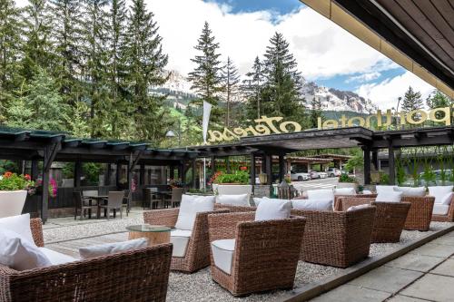 a restaurant with wicker chairs and tables in front of a building at Sporthotel Teresa in Badia