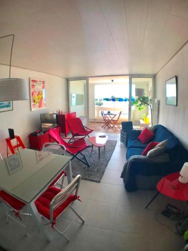 - un salon avec des chaises rouges et un canapé bleu dans l'établissement AS13993- P2 Vue mer avec piscine direct sur plage, au Grau-du-Roi