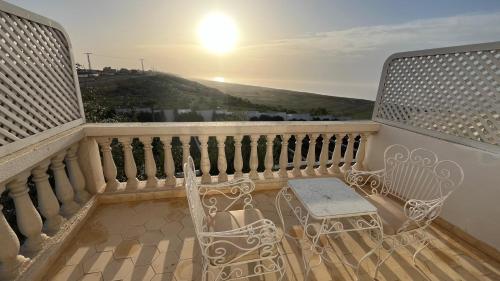 a balcony with two chairs and a table and the sunset at Villa La Falaise in Oualidia