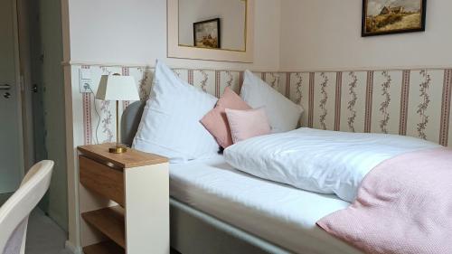 a bed with white sheets and pink pillows on it at Schlosshotel Wilhelmsthal in Schäferberg