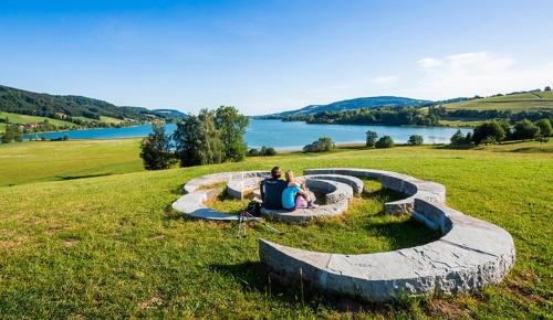 a woman sitting on a stone bench near a lake at CK Apartment in Oberhofen am Irrsee