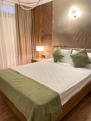a bedroom with a large white bed with green pillows at Şerefe Hotel Alaçatı in Alaçatı