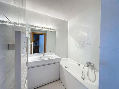 une salle de bain blanche avec un lavabo et un miroir dans l'établissement Auron, steps from central square, à Auron