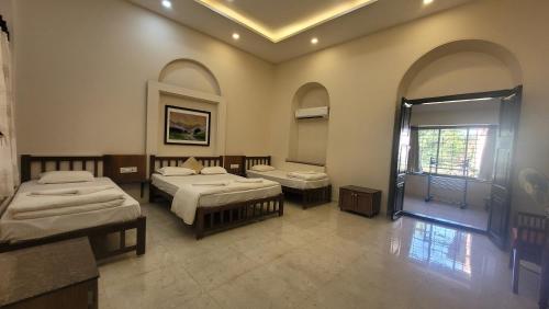 a large room with two beds and a mirror at Madhuvan Retreat Resort Amba in Chandoli