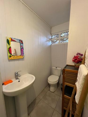 a white bathroom with a sink and a toilet at Location tropical in Sainte-Anne