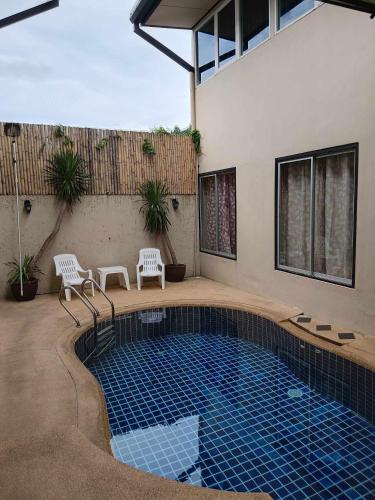 a swimming pool with two chairs next to a house at Infinity Boutique Hotel Kata Beach in Kata Beach