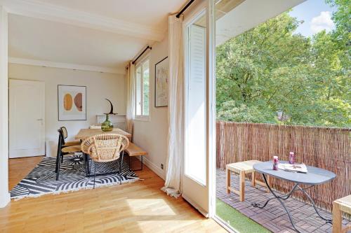 un salon avec une table et une grande fenêtre dans l'établissement Lumineux 3P spacieux & chaleureux - Hôpital américain, à Neuilly-sur-Seine