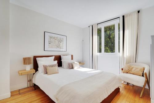 une chambre blanche avec un grand lit et une chaise dans l'établissement Lumineux 3P spacieux & chaleureux - Hôpital américain, à Neuilly-sur-Seine